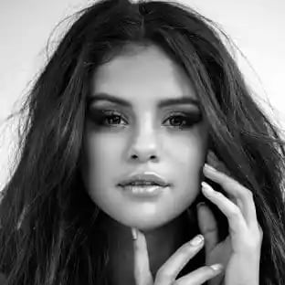 Black and white portrait of a young woman with long dark hair, hand raised to her face, looking directly at camera